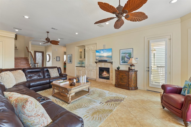 tiled living room featuring a fireplace, ceiling fan, and ornamental molding