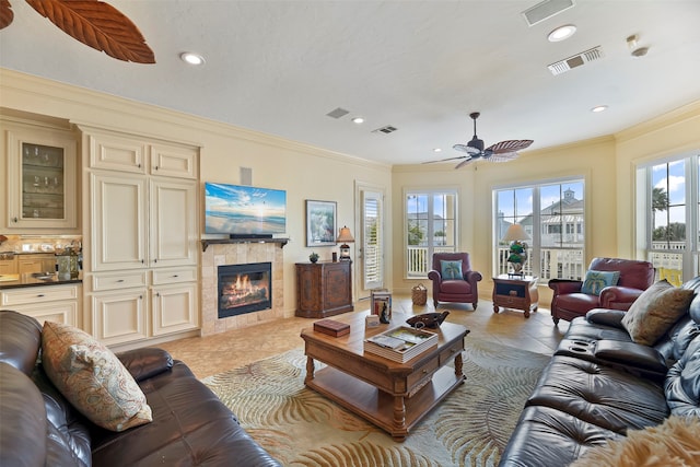 living room with ornamental molding, a fireplace, light tile patterned floors, and ceiling fan