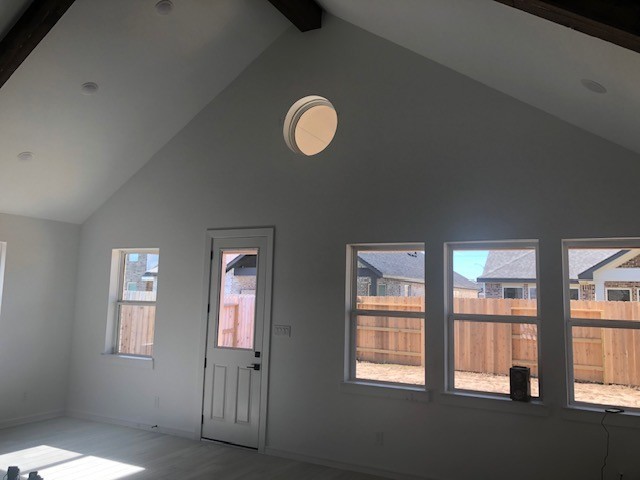 entryway with beam ceiling, hardwood / wood-style floors, high vaulted ceiling, and a healthy amount of sunlight