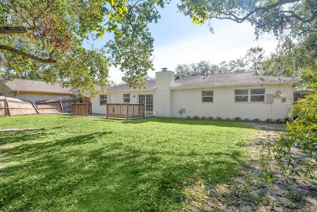 back of property with a lawn and a deck