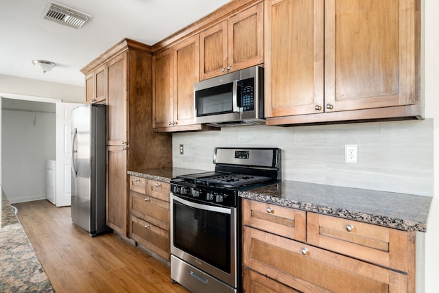 kitchen featuring backsplash, light wood-type flooring, and appliances with stainless steel finishes