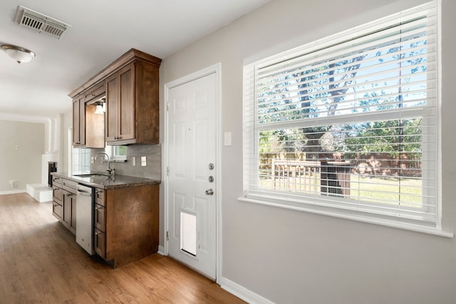 kitchen featuring decorative backsplash, a healthy amount of sunlight, dishwasher, and light hardwood / wood-style flooring