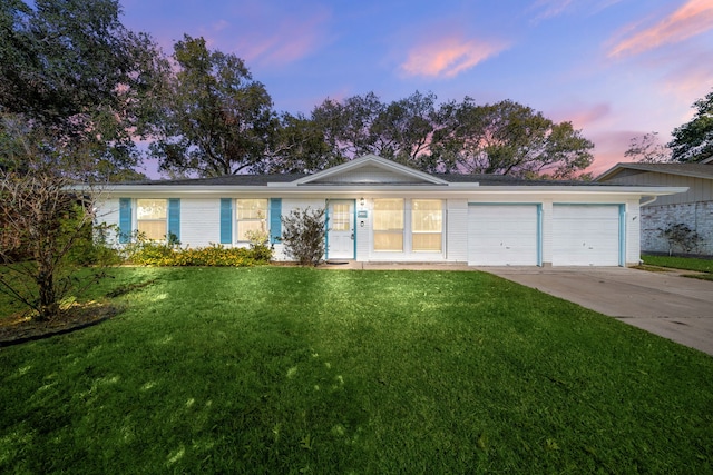 single story home featuring driveway, a yard, and an attached garage