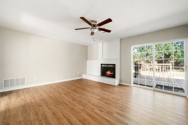 unfurnished living room featuring ceiling fan, light wood-type flooring, and a fireplace