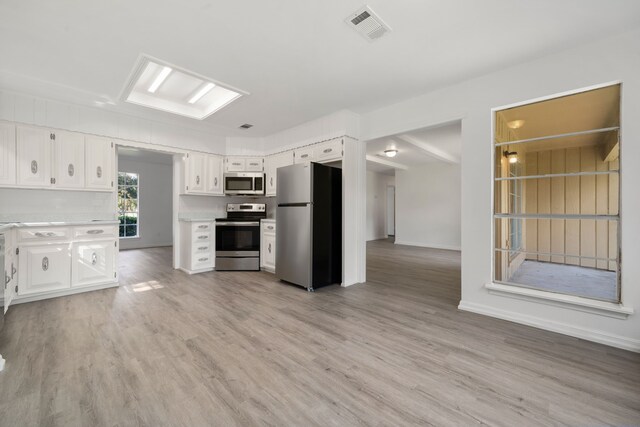 kitchen with stainless steel appliances, white cabinets, and light wood-type flooring