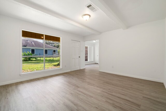 unfurnished room with wood-type flooring and beam ceiling