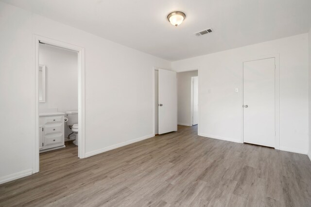 unfurnished bedroom featuring connected bathroom, a closet, and light hardwood / wood-style flooring