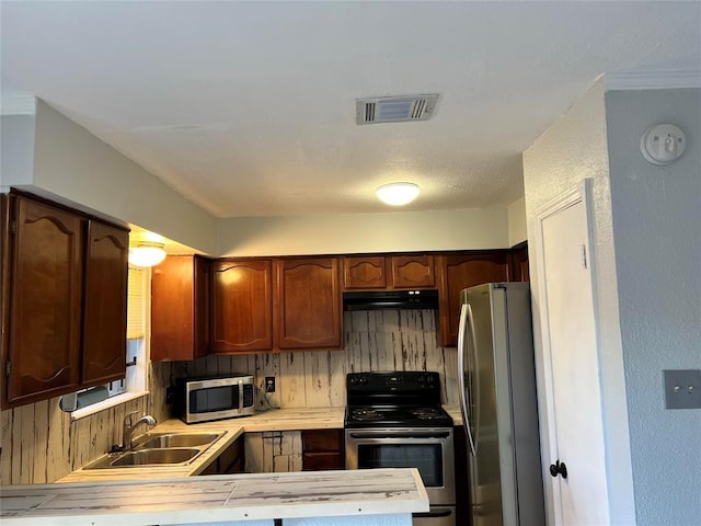 kitchen with kitchen peninsula, appliances with stainless steel finishes, sink, and decorative backsplash