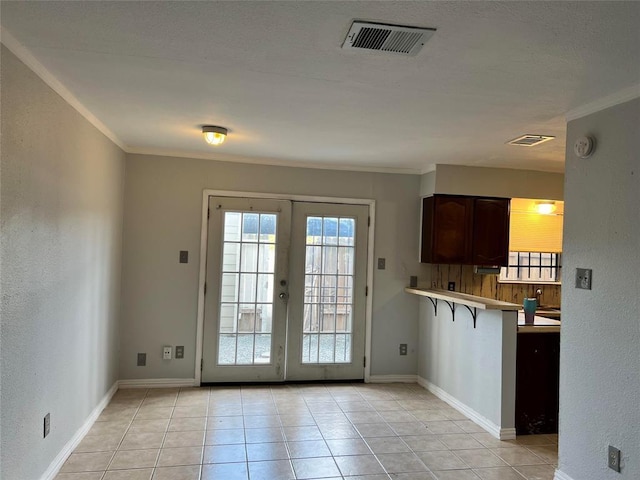 doorway to outside featuring crown molding, french doors, and light tile patterned flooring