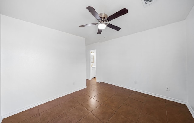 spare room with ceiling fan and dark tile patterned floors