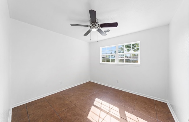 empty room with ceiling fan and dark tile patterned floors