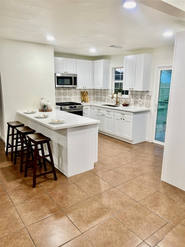 kitchen featuring white cabinets, a kitchen bar, stainless steel appliances, and sink