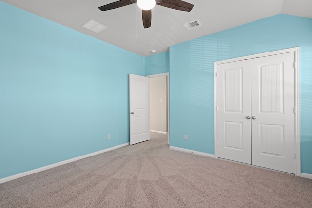 unfurnished bedroom featuring a closet, vaulted ceiling, light colored carpet, and ceiling fan