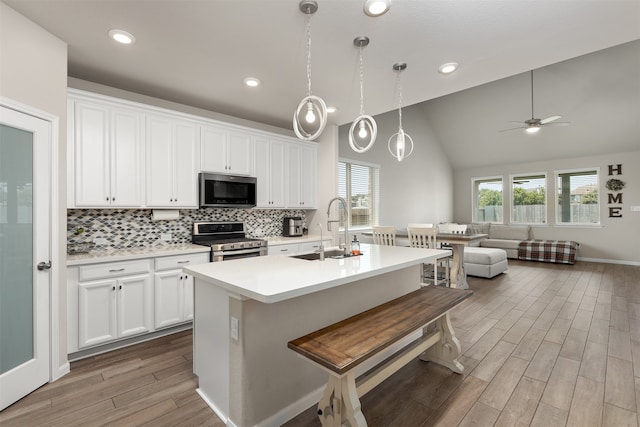 kitchen featuring white cabinetry, appliances with stainless steel finishes, sink, an island with sink, and light hardwood / wood-style flooring