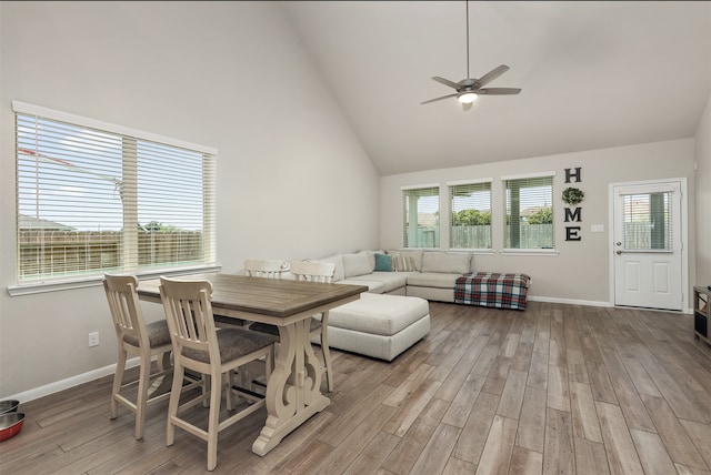 dining area featuring high vaulted ceiling, light wood-type flooring, and a healthy amount of sunlight