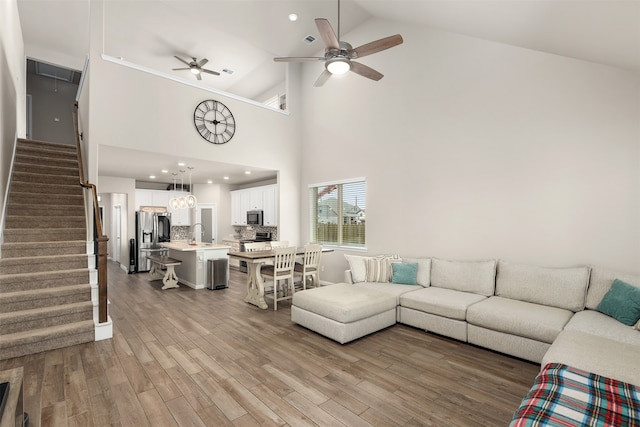 living room featuring high vaulted ceiling, sink, hardwood / wood-style flooring, and ceiling fan