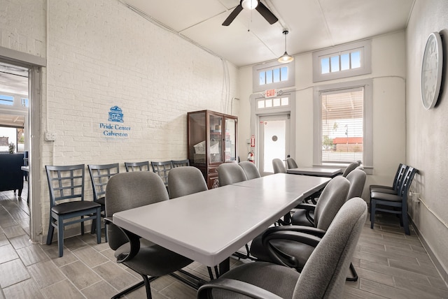 dining room with wood-type flooring, ceiling fan, and a high ceiling