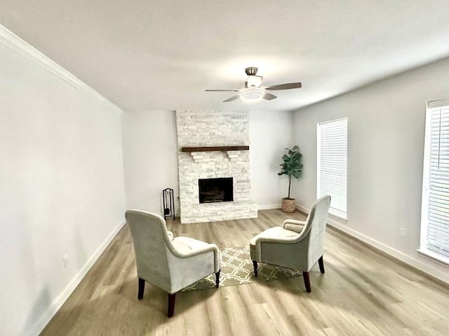 living room featuring a textured ceiling, hardwood / wood-style flooring, ceiling fan, crown molding, and a fireplace