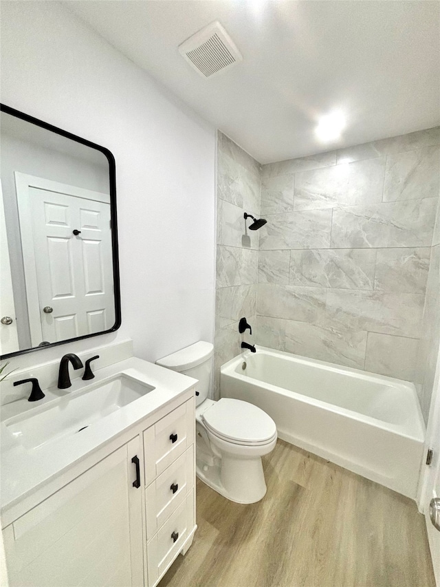 full bathroom with hardwood / wood-style floors, vanity, toilet, and tiled shower / bath combo