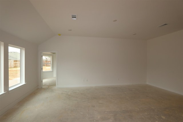 unfurnished room with visible vents, baseboards, and lofted ceiling