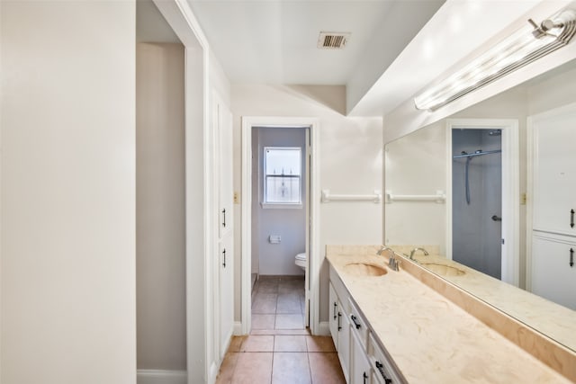 bathroom featuring toilet, a shower, vanity, and tile patterned flooring