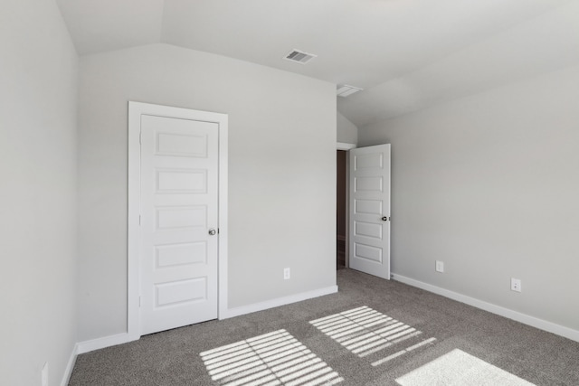 unfurnished bedroom with dark carpet and vaulted ceiling