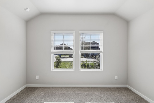 carpeted spare room featuring lofted ceiling