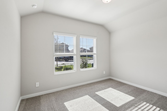 carpeted spare room with lofted ceiling