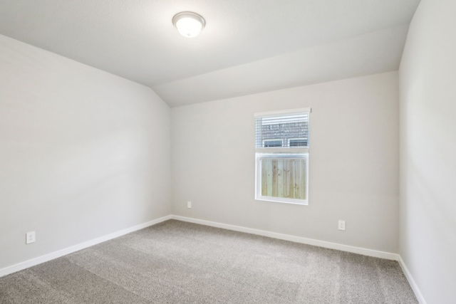 carpeted spare room with lofted ceiling