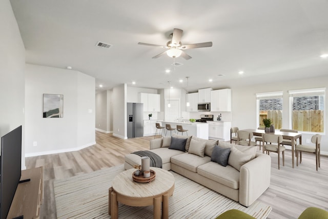 living room with light hardwood / wood-style flooring and ceiling fan