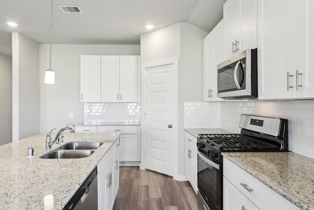 kitchen featuring sink, stainless steel appliances, light stone countertops, white cabinets, and decorative light fixtures