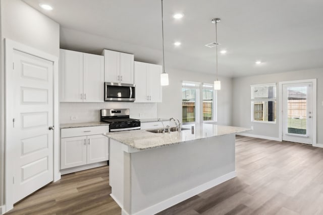 kitchen with white cabinetry, appliances with stainless steel finishes, a kitchen island with sink, and pendant lighting