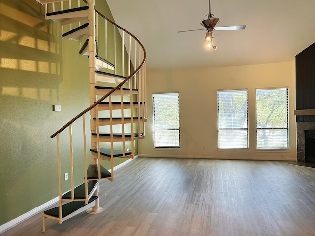 stairs featuring wood-type flooring, ceiling fan, and a fireplace