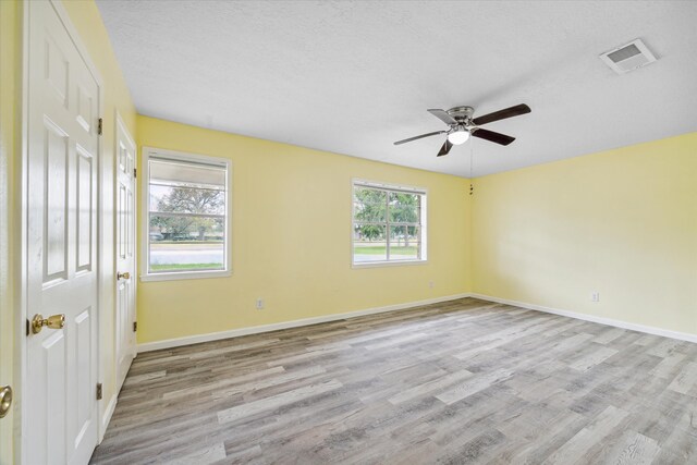 spare room with ceiling fan, light hardwood / wood-style floors, and a textured ceiling