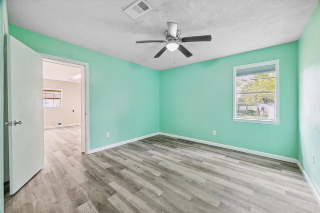 spare room featuring a textured ceiling, light hardwood / wood-style floors, and ceiling fan