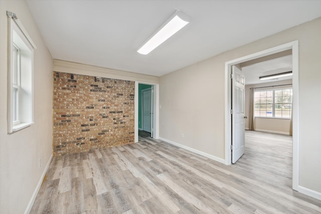 spare room featuring light hardwood / wood-style flooring and brick wall