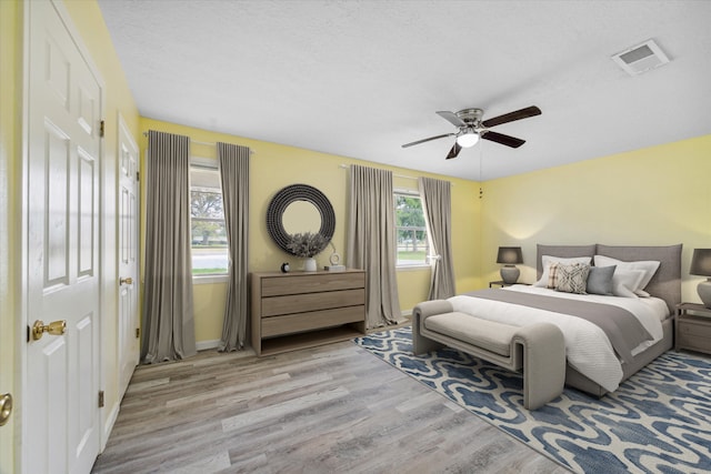 bedroom featuring ceiling fan, a textured ceiling, and light hardwood / wood-style flooring