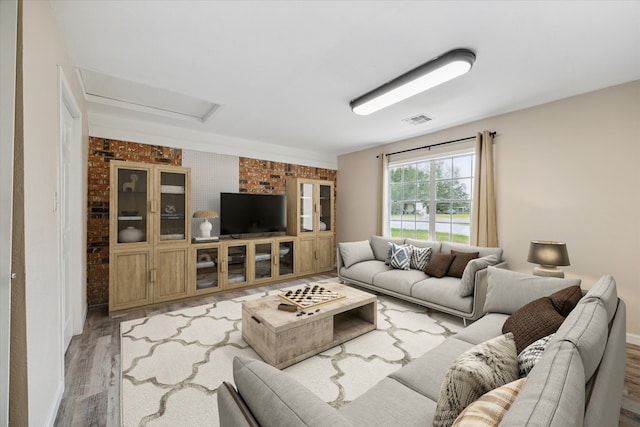 living room with brick wall and hardwood / wood-style flooring