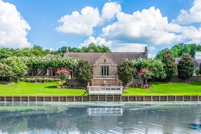 rear view of house featuring a water view and a yard