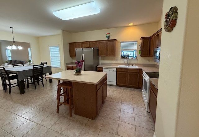 kitchen with light tile patterned floors, sink, a kitchen island, and appliances with stainless steel finishes