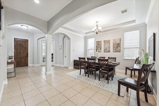 tiled dining room with a raised ceiling, a wealth of natural light, a notable chandelier, and crown molding