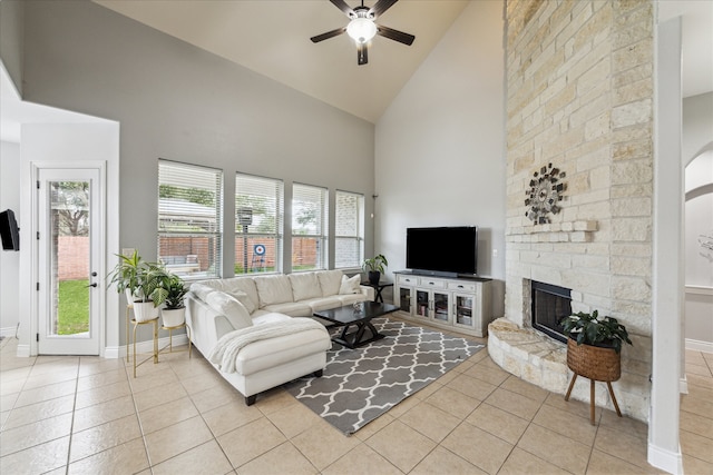 tiled living room featuring high vaulted ceiling, ceiling fan, and a stone fireplace