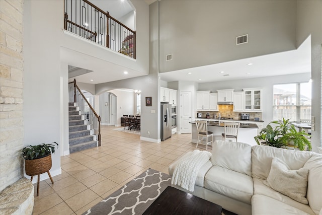 living room with sink, a towering ceiling, and light tile patterned flooring