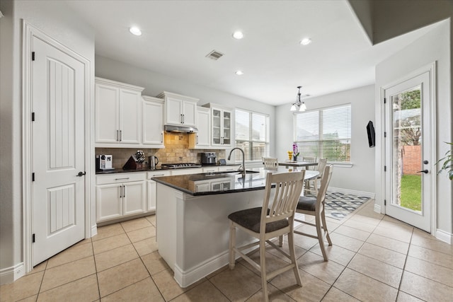 kitchen featuring sink, white cabinetry, a wealth of natural light, and an island with sink