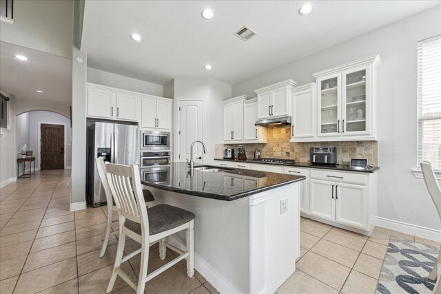 kitchen with white cabinets, appliances with stainless steel finishes, tasteful backsplash, and a kitchen island with sink