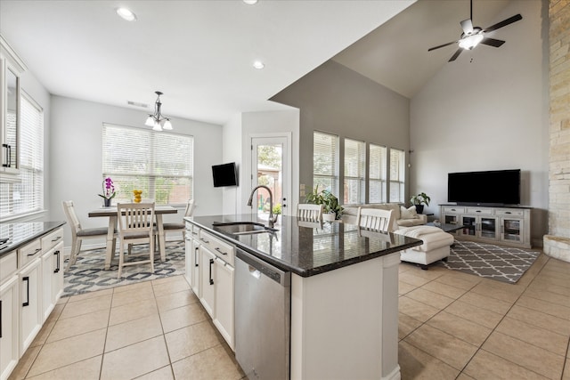 kitchen featuring sink, light tile patterned floors, stainless steel dishwasher, a center island with sink, and white cabinets