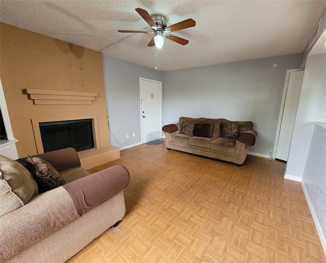 living room featuring a fireplace, ceiling fan, a textured ceiling, and light parquet floors