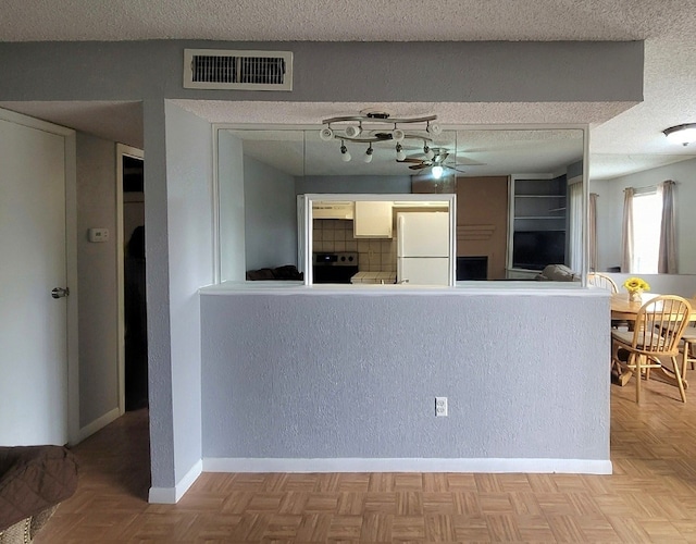 kitchen featuring ceiling fan, a textured ceiling, light parquet floors, stainless steel stove, and white fridge