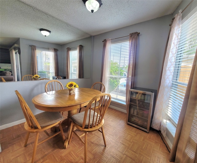 dining room featuring plenty of natural light, wine cooler, a textured ceiling, and light parquet flooring