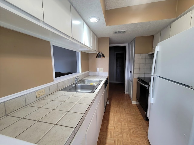 kitchen featuring white fridge, electric stove, white cabinetry, sink, and tile countertops